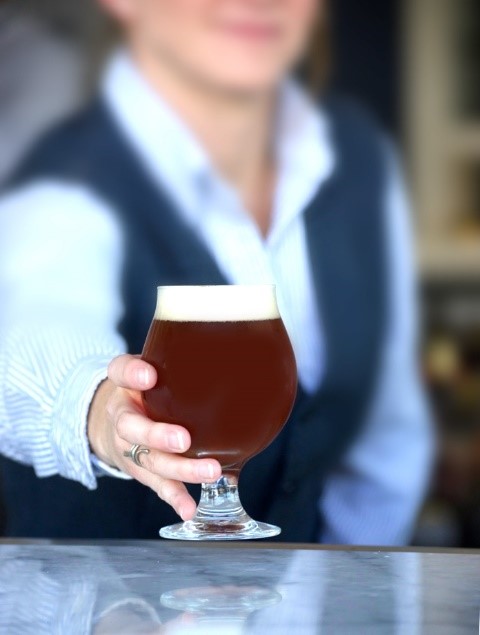 A bartender handing a beer toward the viewer