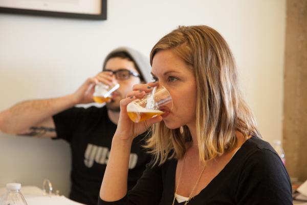 Two people involved in a beer tasting exercise. Both are drinking from beer tasting cups and evaluating the flavors and aromas.